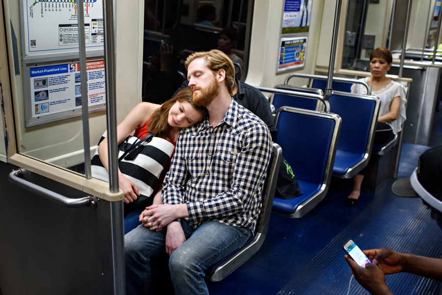 An exhausted couple relax on the subway on the way to cira green for their engagement session.